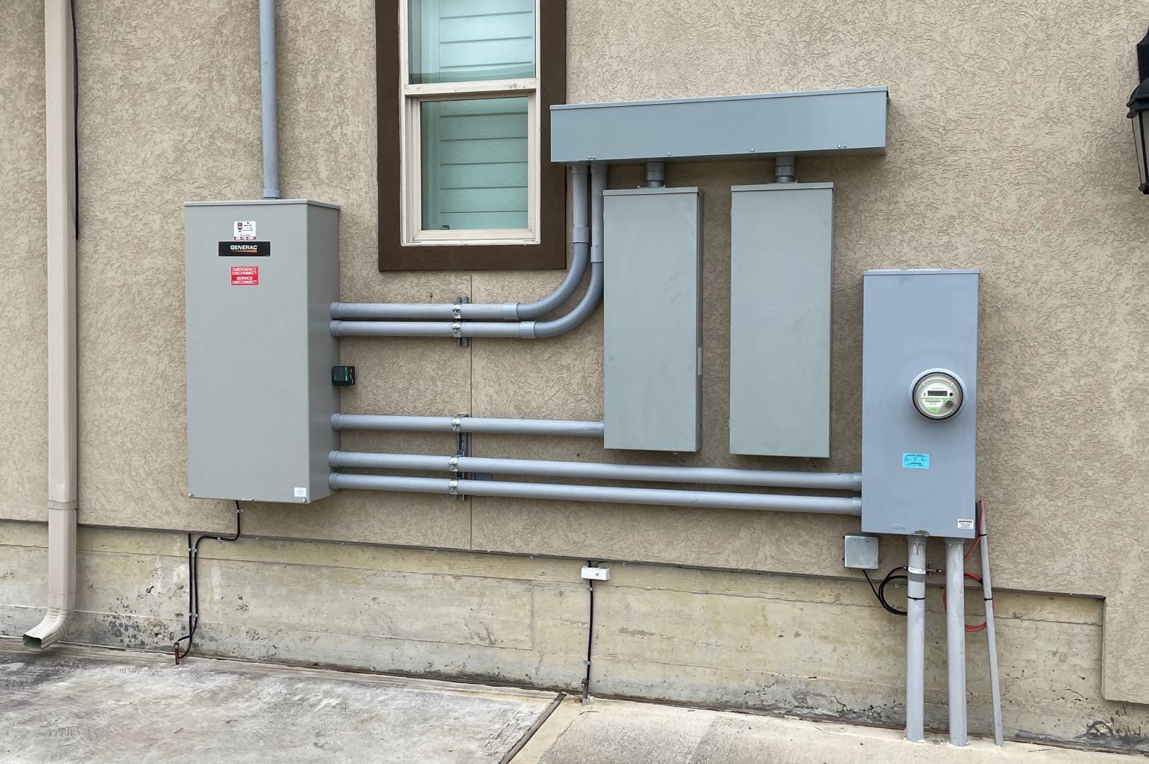 Residential electrical panels, meter equipment, and Generac transfer switch installed on exterior home wall in La Porte, Tx